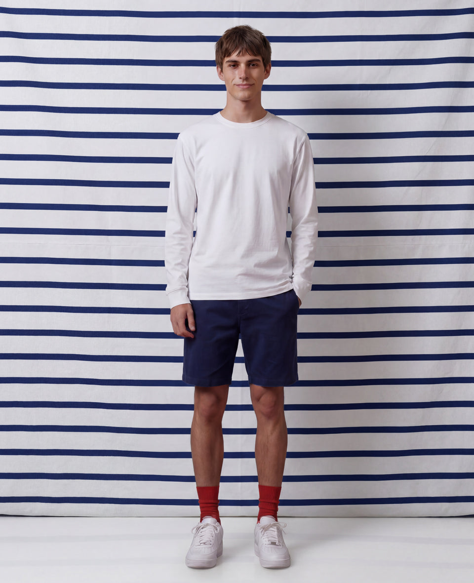 Man wearing white t-shirt, navy trousers, red Democratique Red Moon ribbed socks and white sneakers, summer style